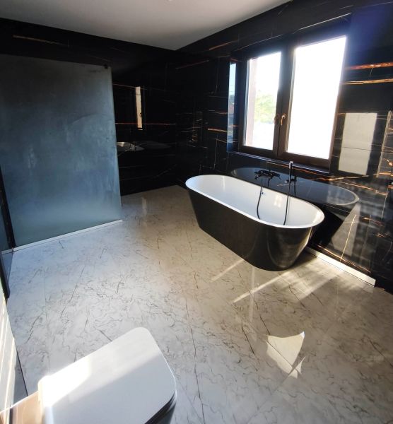 Elegantes Badezimmer mit freistehender Badewanne und schwarzen Wänden in einem Einfamilienhaus.