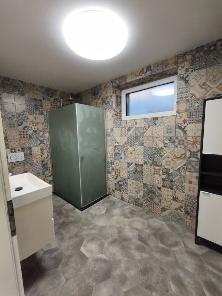 Ein Badezimmer in einem Einfamilienhaus mit gemusterten Fliesen und einer Duschkabine.