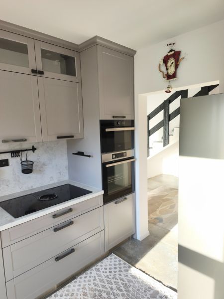 Küche in einem Einfamilienhaus mit eingebautem Ofen, grauen Schränken und Induktionskochfeld.