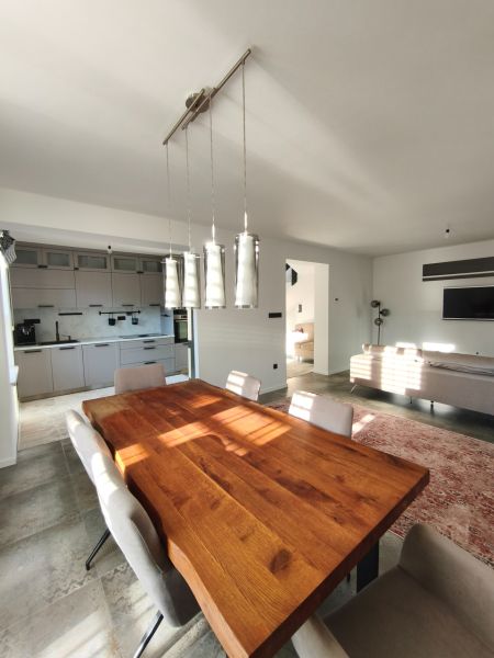 Esstisch aus Massivholz in einem Einfamilienhaus mit Küche und Wohnzimmer auf einem Boden mit Holzdekor.