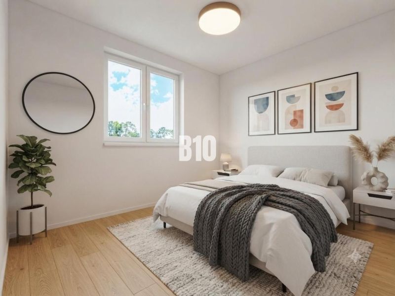 Schlafzimmer mit Bett, Holzboden, Pflanze und rundem Spiegel in einem Einfamilienhaus.