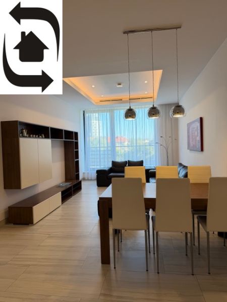 Wohnzimmer mit Holzboden, Esstisch und verglaster Wand.