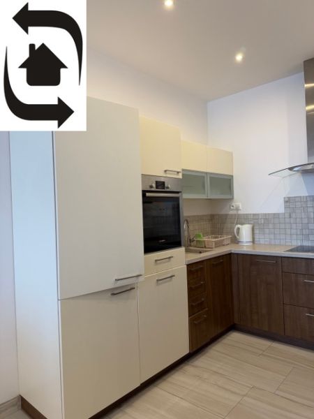 Küche in einer 3-Zimmer-Wohnung mit weißen und hölzernen Schränken und Geräten.