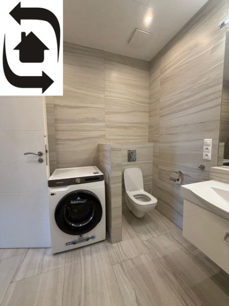 Badezimmer mit Waschmaschine und Toilette in einer 3-Zimmer-Wohnung, Fliesen mit Steinmuster.
