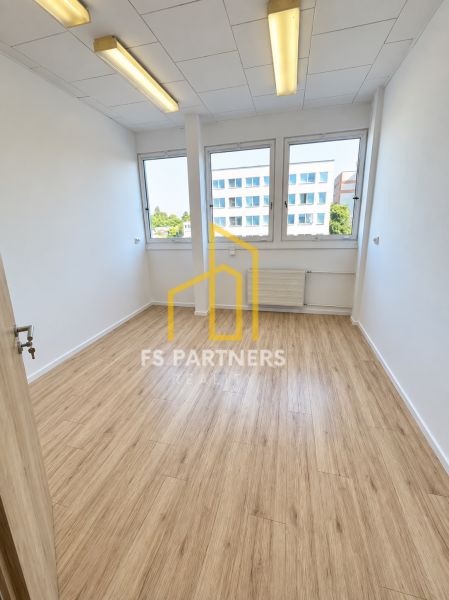 Ein Büro mit einem Boden in Holzoptik, Innenraum mit großen Fenstern und Deckenbeleuchtung.