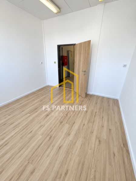Ein Büro mit weißen Wänden und einem Boden in Holzoptik.