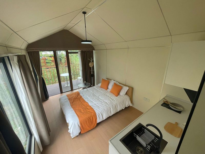 Eine Hütte mit Holzboden, ein einfaches Bett, eine kleine Küche und ein Balkon.
