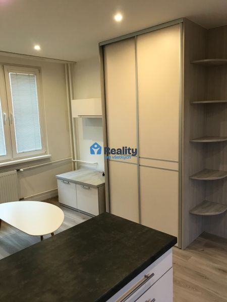 Einzimmerwohnung mit weißen Möbeln, Einbauschrank und Boden mit Holzdekor.