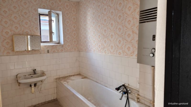 Badezimmer im Einfamilienhaus mit Badewanne, Waschbecken und Gasboiler.