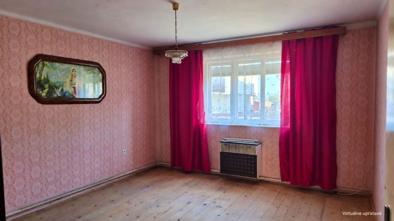 Ein Zimmer in einem Einfamilienhaus mit rosa Tapeten und einem Boden in Holzoptik.