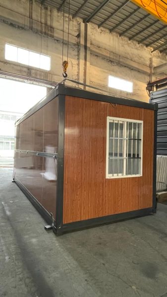 Kompaktes Häuschen in einer Halle mit Holzboden und Gitterfenster.