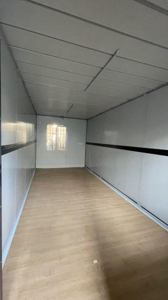 Das Innere der Hütte mit einem Boden in Holzoptik, weißen Wänden und einem kleinen Fenster.
