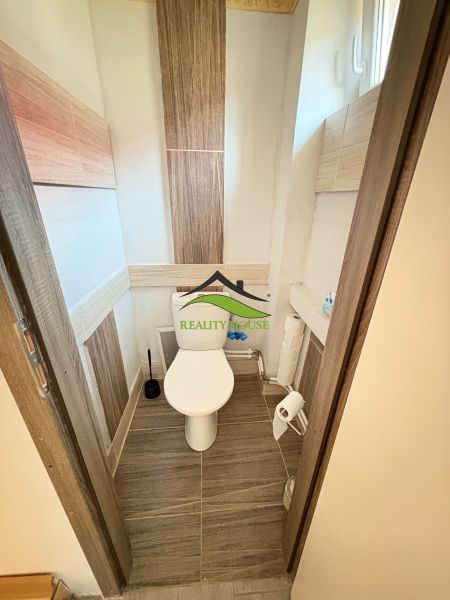 Toilette im Einfamilienhaus mit Keramikfliesen und schmalem Fenster.
