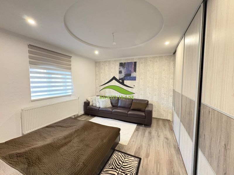 Ein Zimmer in einem Einfamilienhaus mit einem Holzboden, einem Sofa und einem Bett.