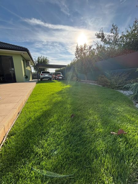 Der Garten beim Einfamilienhaus in der Feigenstraße in Bernolákovo mit einem sonnigen Wohnsitz und Grünflächen.