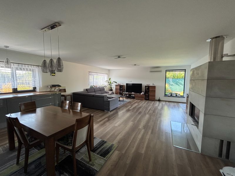 Wohnzimmer in einem Einfamilienhaus mit Holzboden, Kamin und Esstisch.