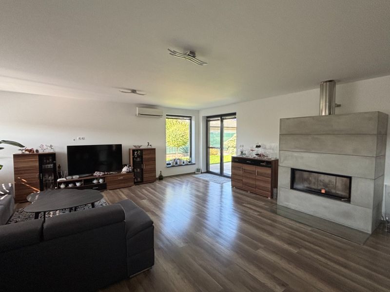 Wohnzimmer in einem Einfamilienhaus mit Sofa, Fernseher, Kamin und Holzboden.