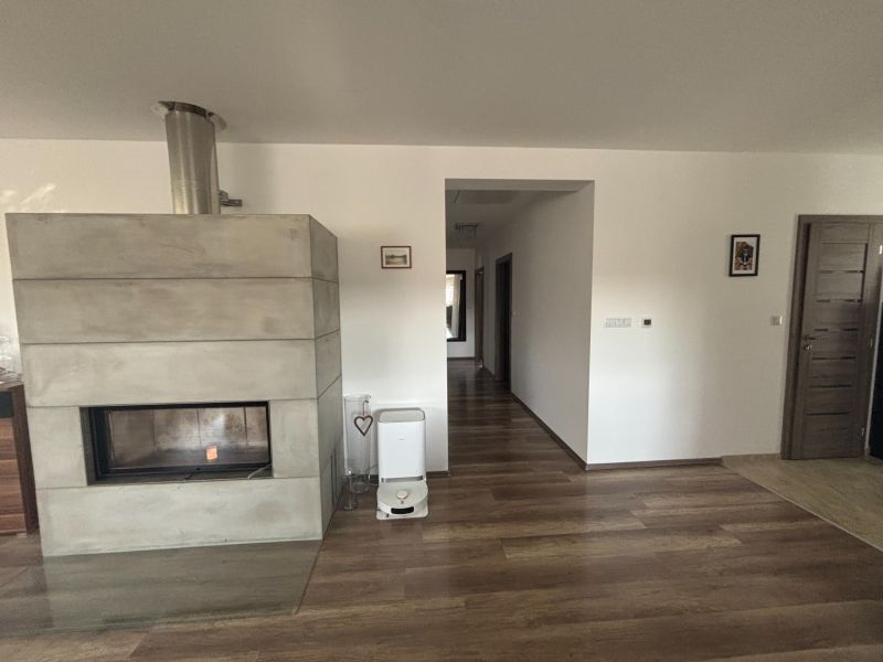 Ein Kamin in einem Einfamilienhaus mit einem Boden in Holzoptik und hellen Wänden.