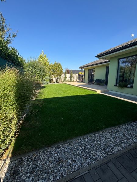 Garten beim Einfamilienhaus in der Figová-Straße in Bernolákovo mit Rasen und Terrasse.