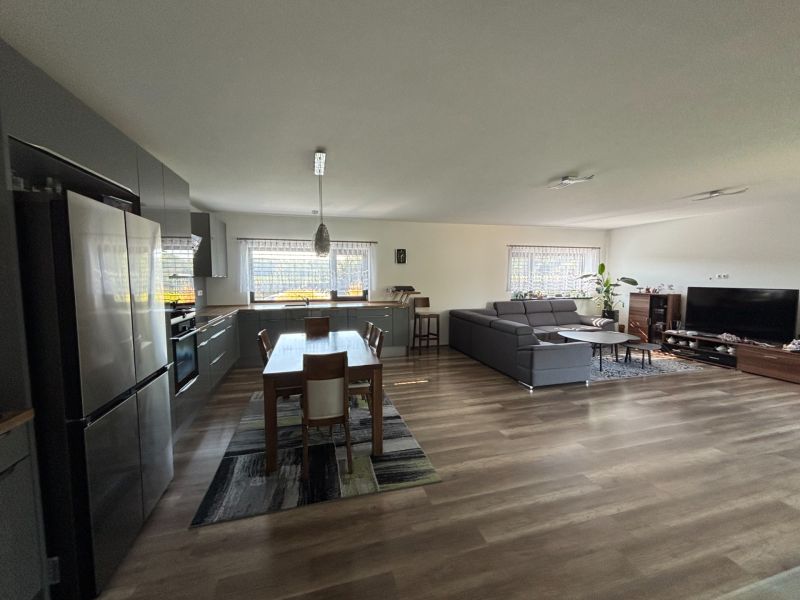 Offenes Interieur eines Einfamilienhauses mit Küche, Esstisch, Sofa und Holzboden.