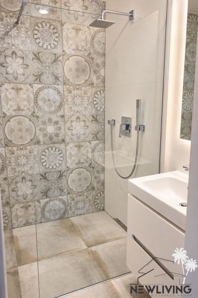 Duschkabine mit dekorativen Fliesen im Badezimmer einer 3-Zimmer-Wohnung.