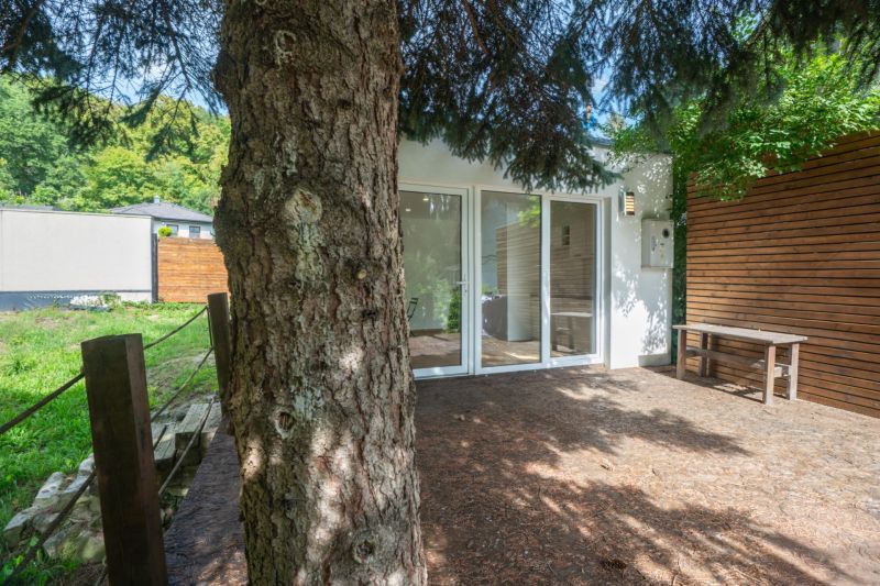 Eine Terrasse bei einem Haus auf Erholungsgrundstücken in Bratislava - Devín, umgeben von Grün und Bäumen.