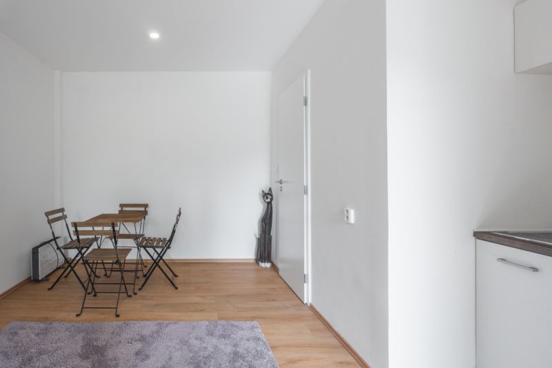 Einfaches Interieur mit Holztisch und Stühlen auf einem Boden mit Holzdekor.