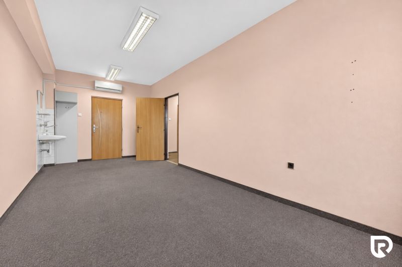 Im Büro gibt es ein Waschbecken, zwei Türen und helle Wände.