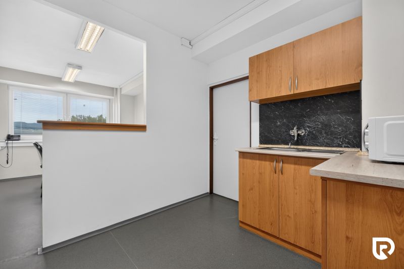Büros mit grauem Boden, Holzdekor der Schränke und einem Fenster für natürliches Licht.