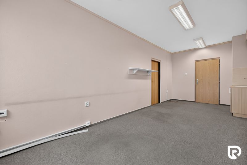 Büros mit rosafarbenen Wänden, grauem Teppichboden, Holztüren, Wandregal und Beleuchtung.