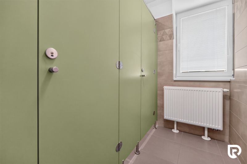 Grüne Türen in Büros, Heizkörper und Fenster mit Rollladen.