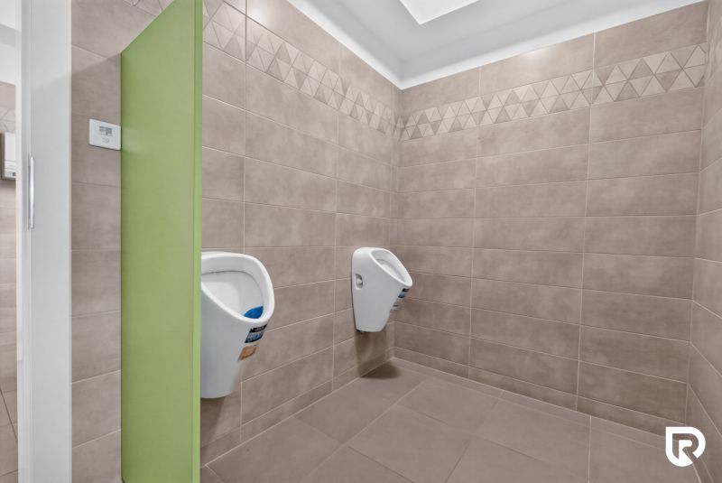 Innenraum eines Büros mit Wandverkleidung und zwei Urinalen.