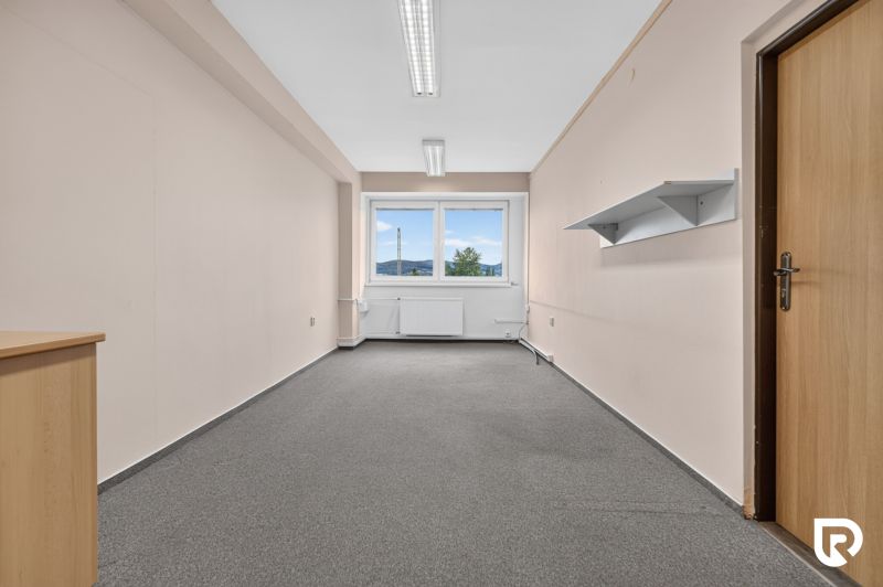 Büros mit Teppichboden, weißen Wänden und einem Fenster, ideal für einen Arbeitsbereich.