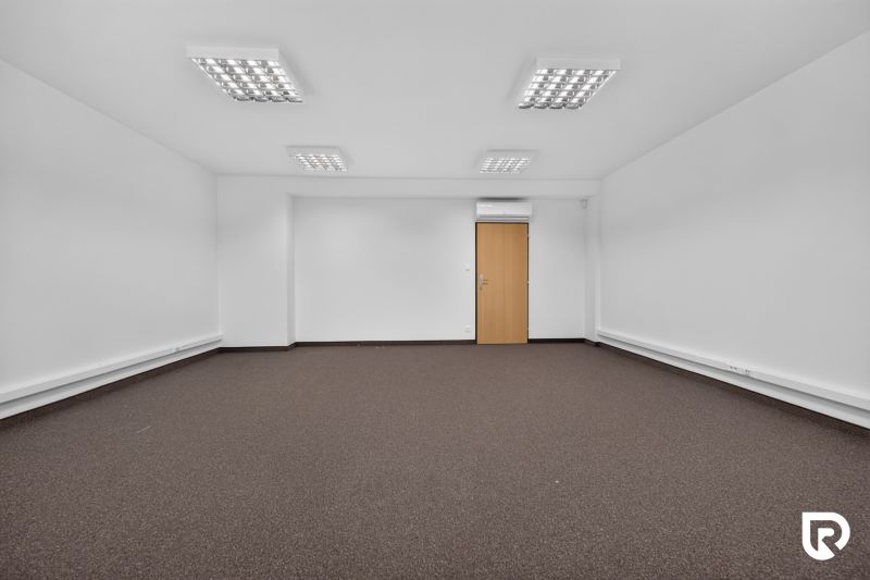 Ein geräumiges Büro mit weißen Wänden und braunem Teppich.