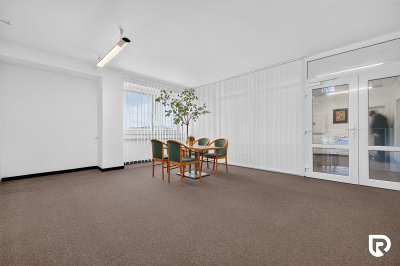 Büros mit Teppichboden, Tisch und Stühlen, Glastüren und großem Fenster.