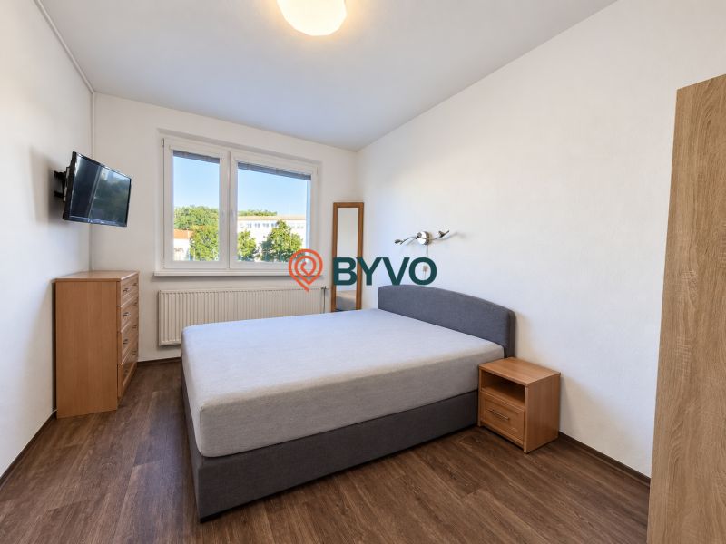 Schlafzimmer in einer 4-Zimmer-Wohnung mit Holzboden und großem Fenster.