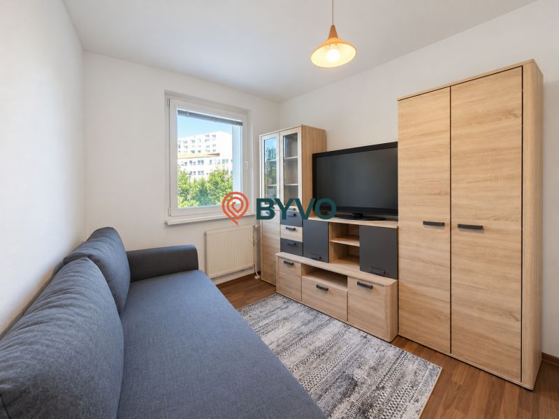 Wohnzimmer in einer 4-Zimmer-Wohnung mit Sofa, Möbeln und Boden in Holzoptik.