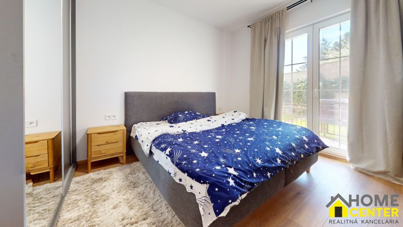 Schlafzimmer in einer 2-Zimmer-Wohnung mit Doppelbett, Nachttischen und Boden in Holzoptik.