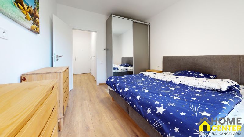 Schlafzimmer mit Bett, Einbauschrank und Boden mit Holzdekor in einer Zweizimmerwohnung.