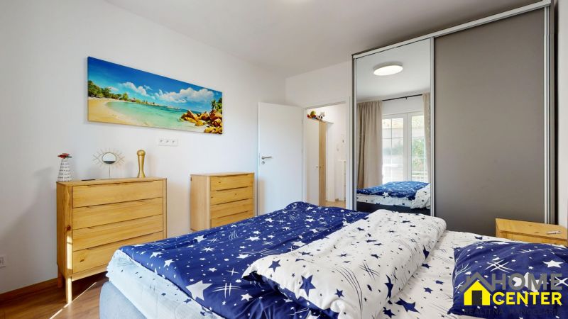 Schlafzimmer in einer 2-Zimmer-Wohnung mit Holzboden, weißen Wänden und einem Bild von einem Strand.