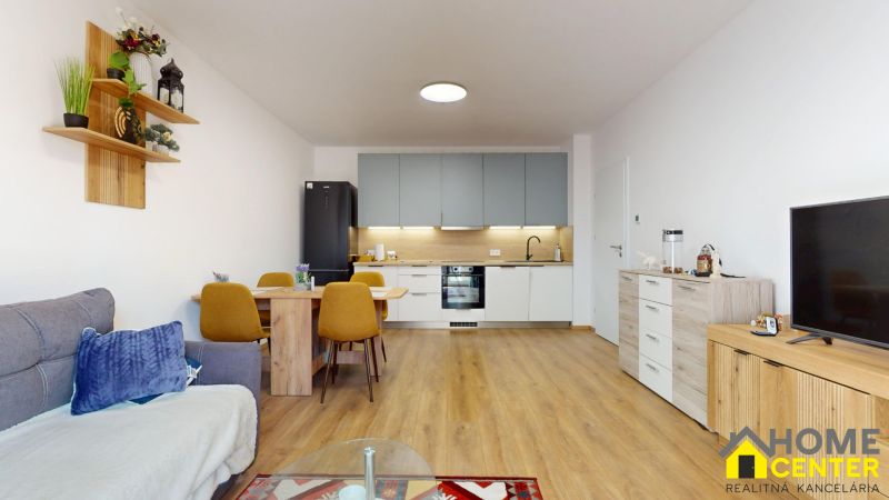 Wohnzimmer mit Küche in einer 2-Zimmer-Wohnung mit Holzboden und Esstisch.