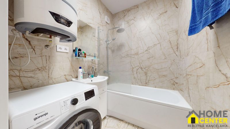 Badezimmer in einer 2-Zimmer-Wohnung mit Waschmaschine, Waschbecken und Badewanne.