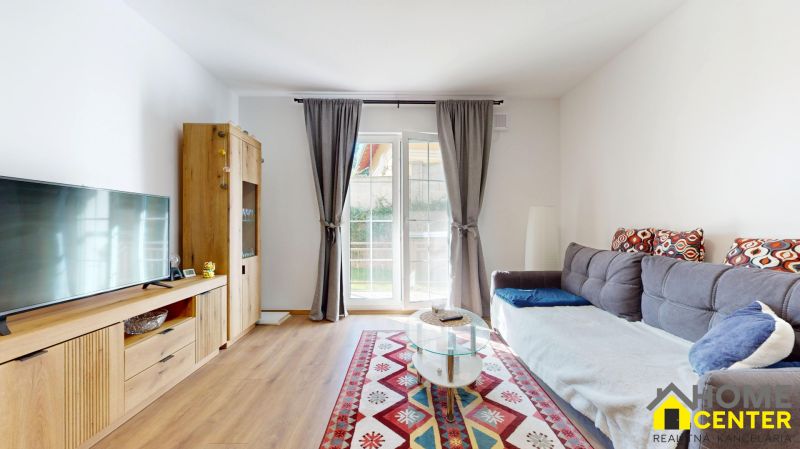 Wohnzimmer einer Zweizimmerwohnung mit Sofa, Fernseher und Holzboden.
