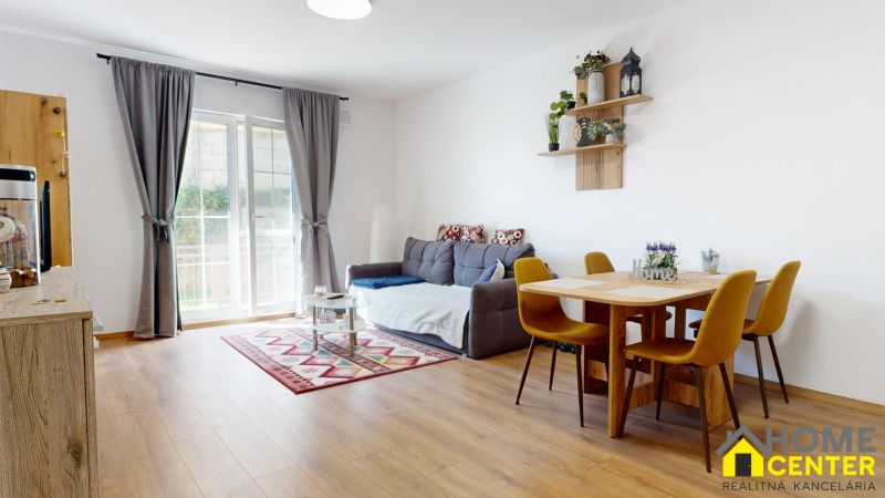 Wohnzimmer mit Sofa, Esstisch und Holzboden in einer Zweizimmerwohnung.