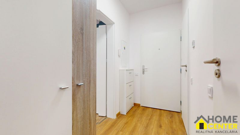 Flur mit weißen Möbeln und Boden in Holzoptik in einer 2-Zimmer-Wohnung.