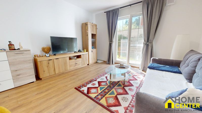 Wohnzimmer in einer 2-Zimmer-Wohnung mit Holzboden und buntem Teppich.