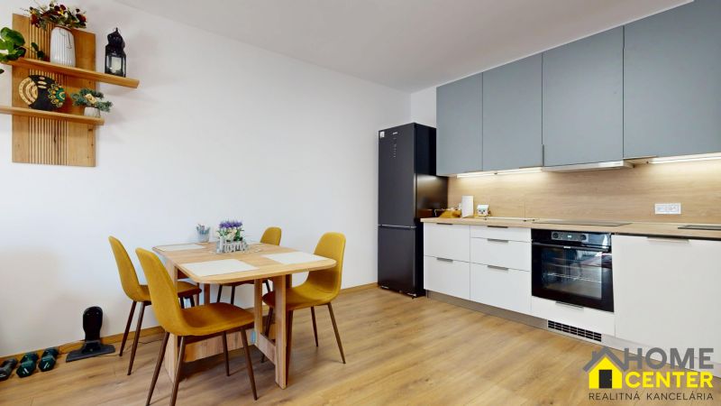 Küche in einer 2-Zimmer-Wohnung mit Holzboden, Esstisch und Geräten.