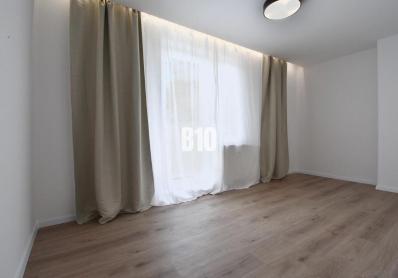 Helles Zimmer mit Holzboden und großem Fenster in einer 4-Zimmer-Wohnung.