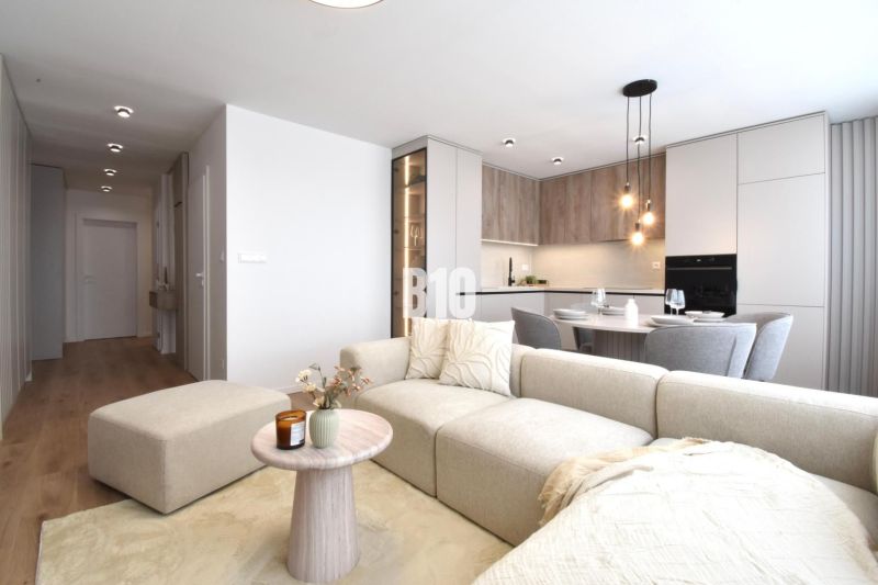 Wohnzimmer mit Küche in einer 4-Zimmer-Wohnung, mit einem Boden in Holzoptik.