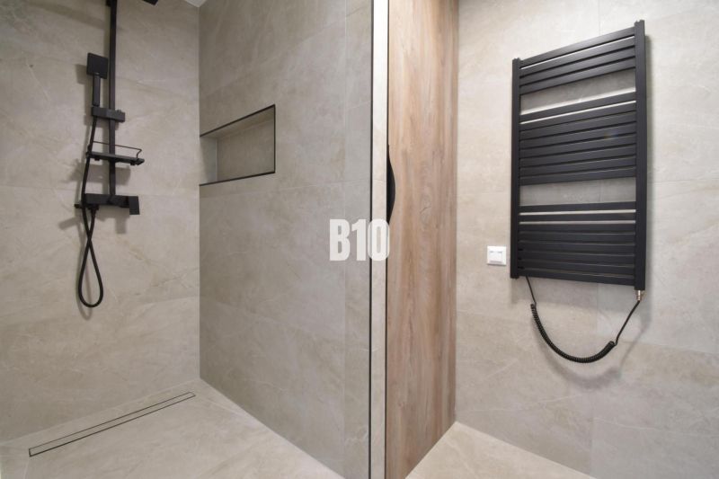 Badezimmer in einer 4-Zimmer-Wohnung mit moderner Dusche und schwarzem Heizkörper.